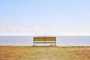 Empty bench on cliff before sea background, peaceful and quiet place for thinking alone photo