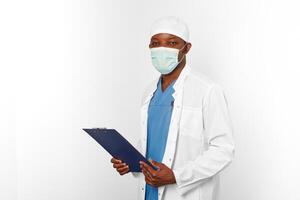 Black surgeon doctor man in white coat cap and surgeon mask holds medical records with diagnosis photo