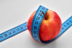 Red apple with measuring tape isolated on white background photo