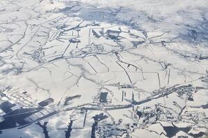 vista aérea sobre las nubes hasta los ríos, campos y caminos cubiertos de nieve, aire fresco helado de invierno foto