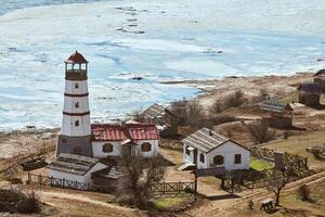 hermoso faro rojo blanco con casas de servicios agrícolas en merzhanovo, rostov en la región de don russia foto