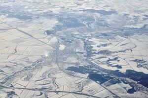 vista aérea del paisaje nublado sobre las nubes hasta ríos, carreteras, ciudades y campos cubiertos de nieve, aire invernal foto