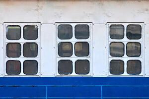 Three cabin windows and portholes on outboard side of ship photo