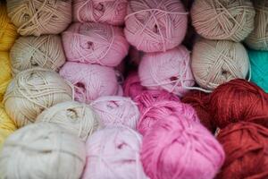 Colored pink red yarn balls in knitting shop, macro photo