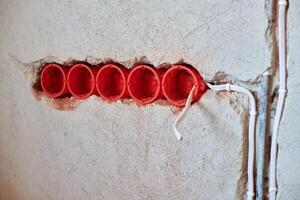 Plastic socket boxes and electrical wires on plastered wall photo