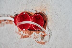 Plastic socket box and electrical wires on plastered wall photo