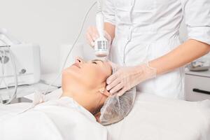 Beautician makes cryotherapy for rejuvenation woman face, anti aging procedure in salon photo