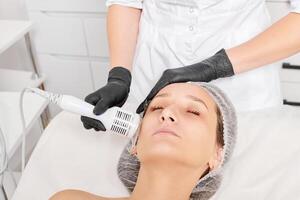 Beautician makes cryotherapy for rejuvenation woman face, anti aging procedure in salon photo