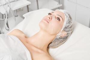 Young woman in sheet mask on face for rehydrate face skin, anti wrinkles procedure in beauty salon photo