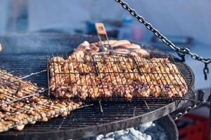 cocinar barbacoa de pollo en una cesta de barbacoa con mango de madera, humo espeso y delicioso foto