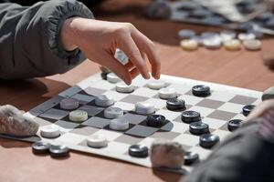 Outdoor checkers tournament on paper checkerboard on table, close up players hands photo