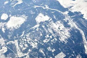 aéreo ver desde avión ventana terminado nubes parte superior a nieve cubierto ríos, campos y carreteras foto