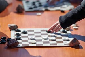 Outdoor checkers tournament on paper checkerboard on table, close up players hands photo