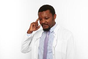 Confused black doctor man with small beard in white robe bright shirt isolated on white background photo