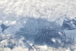 Aerial cloudscape view over clouds top to snow covered rivers, roads, cities and fields, winter air photo