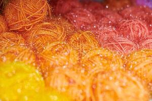Bolas de hilo de color naranja y rojo en tejeduría, macro foto