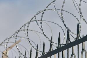 Barbed wire on fence, steel grating fence with barbs photo