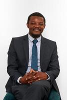 Smiling african american black man in business suit sitting on chair isolated on white background photo