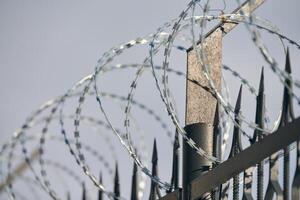 Barbed wire on fence, steel grating fence with barbs photo