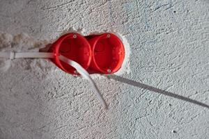 Plastic socket box and electrical wires on plastered wall photo