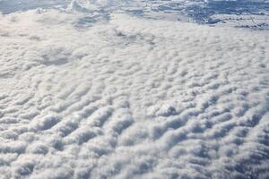Over clouds top view from aircraft window, thick white blue clouds looks like soft foam photo