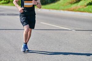 Athletic man jogging in sportswear on city road photo