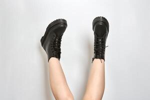 Woman legs in black combat boots on high heel platform with lug soles upside down, white background photo