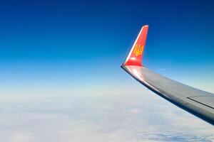 Airplane wing with coat of arms of Ukraine over clouds aerial top view from aircraft window photo