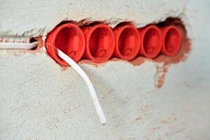 cajas de enchufe de plástico y cables eléctricos en la pared enyesada foto