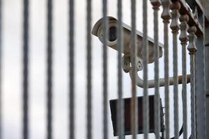 IP CCTV security camera and iron fence, urban cityscape photo