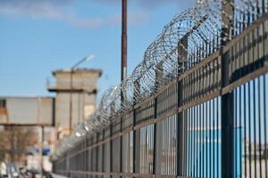 Barbed wire on fence, steel grating fence with barbs photo