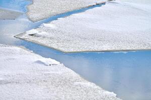 hielo agrietado de río congelado, agua azul, textura de hielo foto