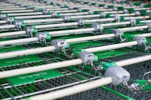 Row of parked shopping carts of trolleys in supermarket photo