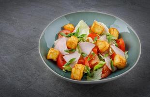 Close-up of salad with ham and halloumi cheese in a bowl on the table 1 photo