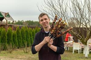 hermoso joven hombre con kebabs en picnic sonriente 1 foto