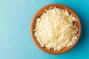 Grated mozzarella cheese in wooden bowl photo