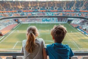 two young spectators from behind watching a football match photo