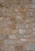 Old coarse panoramic stone wall made of various square natural stones in beige, ocher and brown photo