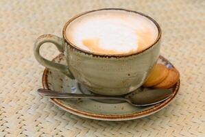 Cup of cappuccino on a table in a cafe. Beautiful foam, white ceramic cup, copy space. photo
