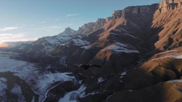 Flight of a vulture in the wild nature of the highlands of the Caucasus. A bird of prey high in the sky against the backdrop of mountains and the setting sun. video