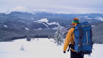 A man with a backpack travels in the mountains in winter. Carpathian mountain range. The concept of travel and active lifestyle. 4K video