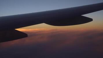 View from the airplane window of the wing, clouds and a beautiful sunset. video