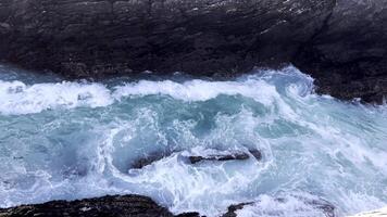 schleppend Bewegung Barrel Welle mit Textur und Wind sprühen, roh natürlich Wunder. schön Küsten Felsen Formationen und abstürzen Meer Wellen. atlantisch Ozean Landschaft mit szenisch Felsen, Klippen video