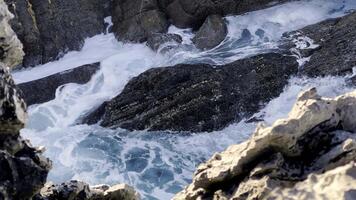 lento movimiento barril ola con textura y viento rociar, crudo natural maravillas hermosa costero rock formaciones y estrellarse mar ondas. atlántico Oceano paisaje con escénico rocas, acantilados video