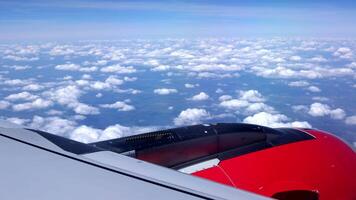aéreo Visão do avião janela dentro a luz do dia. aéreo Visão do cloudscape dentro alvorecer através avião janela. lado Visão a partir de a vermelho turbina. asa do a avião vôo acima branco nuvens contra azul céu video