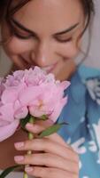 giovane donna riceve mazzo di fiori. contento ragazza Tenere mazzo di peonie. femmina presse un' mazzo di rosa peonie per sua il petto e annusando fiori, lento movimento. internazionale donne giorno video