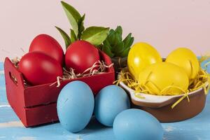 Easter eggs of different colors in a basket and pots with straw photo