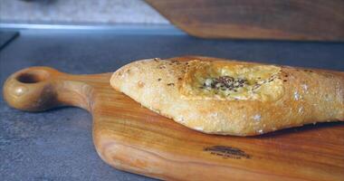 Home kitchen. Khachapuri with cheese and herbs from the oven on a wooden board video