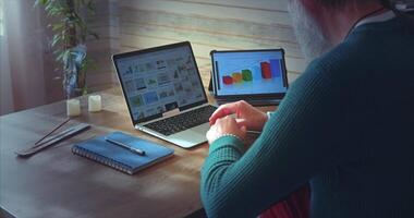 Home Office. A mature man with a beard analyzes growth charts on a laptop at a table video