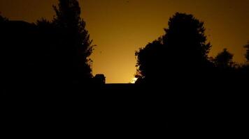 auto In arrivo giù il collina con il sole nascondiglio fra case e alberi a tramonto video